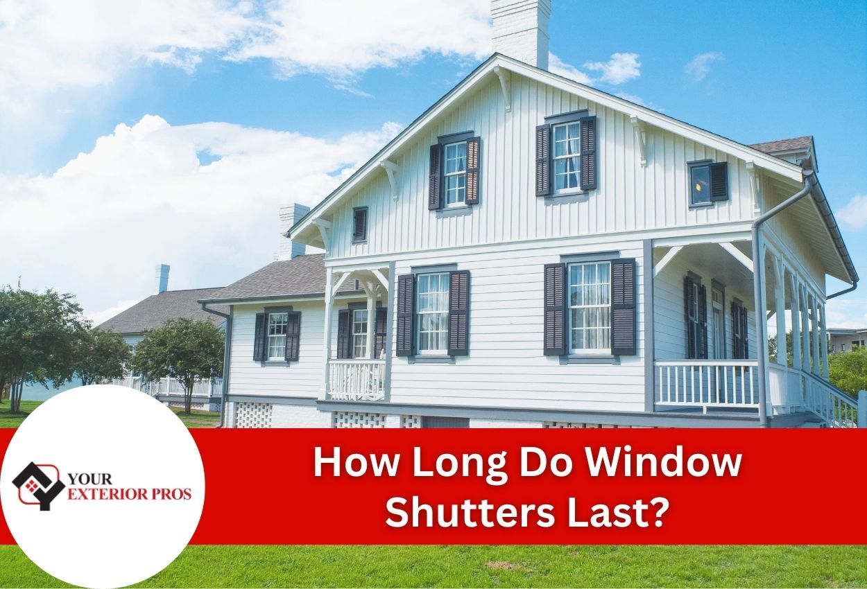 White farmhouse with black shutters and front porch under blue sky